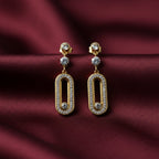 SVORA gold tone stainless steel dangle earrings with cubic zirconia and pavé connector detail.