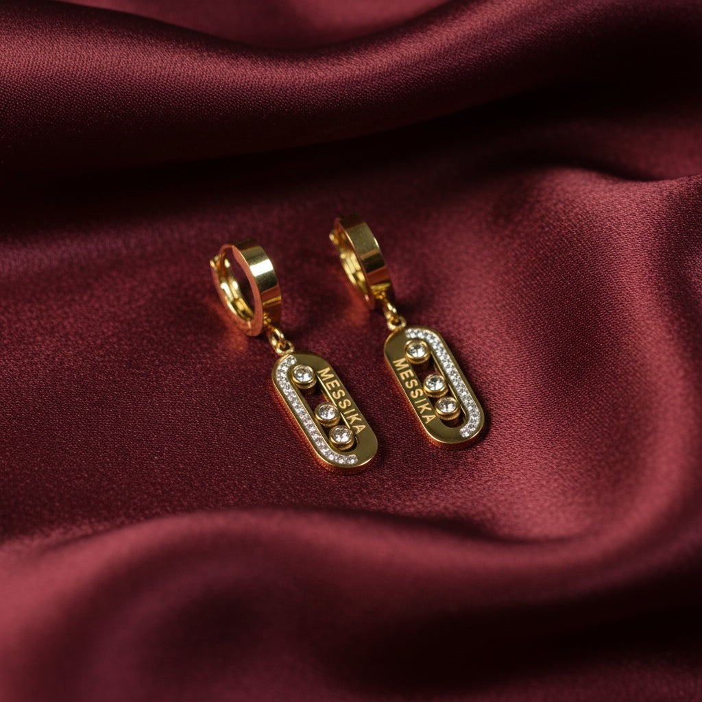 SVORA gold tone stainless steel dangle earrings with cubic zirconia stones and high polish finish.