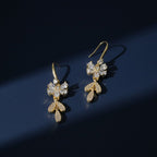 SVORA gold-tone stainless steel dangle earrings with clear cubic zirconia bow and leaf details.