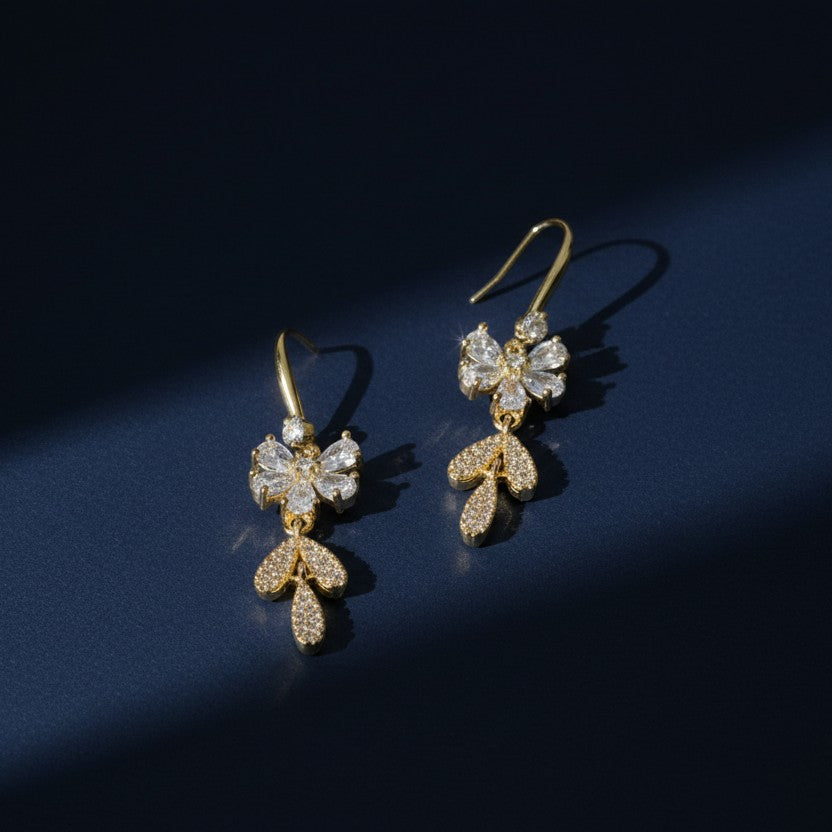 SVORA gold-tone stainless steel dangle earrings with clear cubic zirconia bow and leaf details.