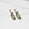 SVORA gold tone stainless steel dangle earrings with cubic zirconia and pavé connector detail.