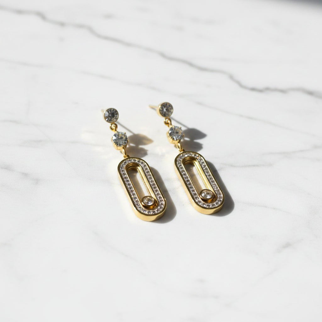 SVORA gold tone stainless steel dangle earrings with cubic zirconia and pavé connector detail.