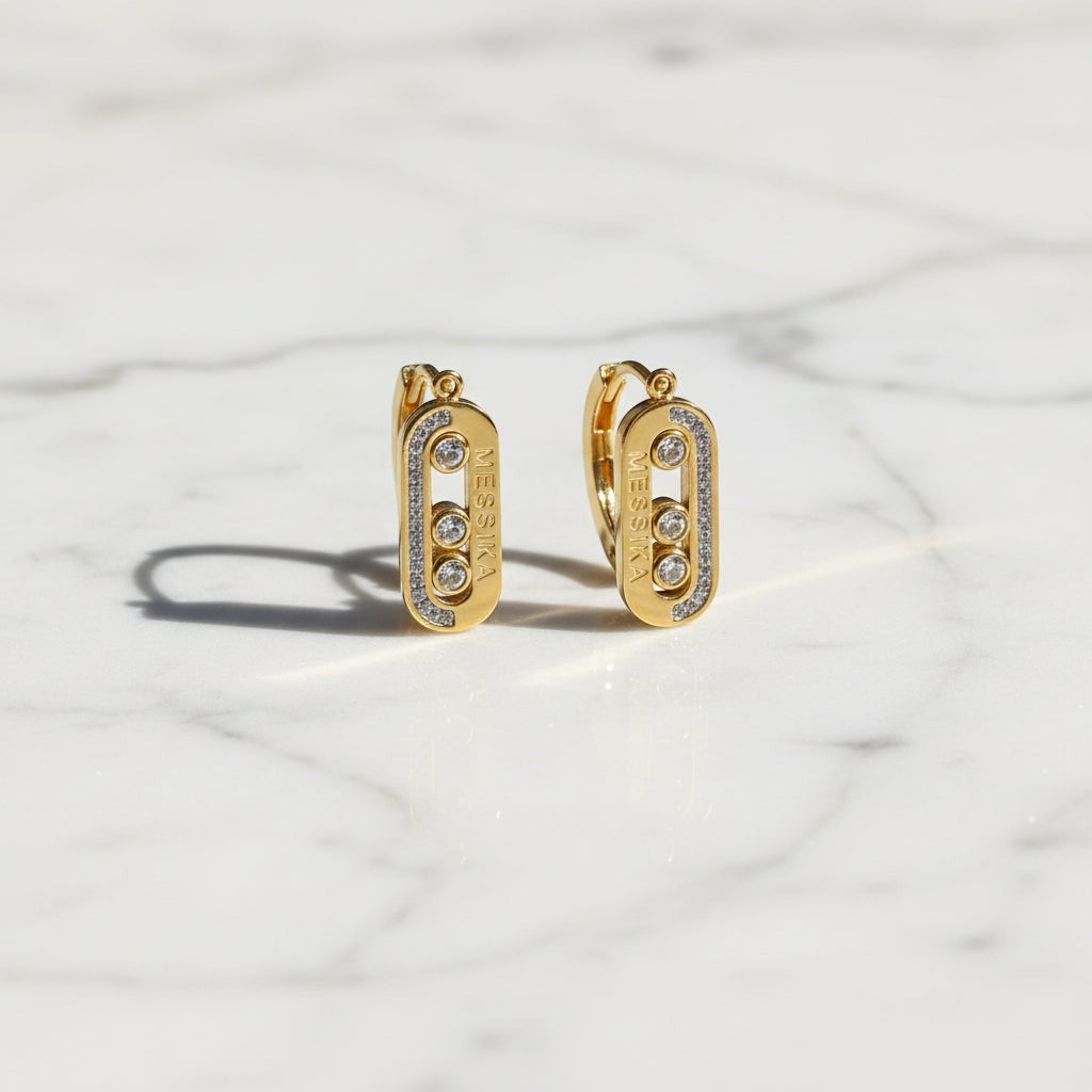SVORA gold tone stainless steel dangler earrings with three cubic zirconia stones and pavé accents.