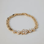 SVORA gold chain bracelet with CZ flowers and leaf links. Adjustable fold-over clasp.