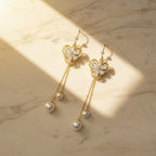 SVORA gold tone dangle earrings with cubic zirconia flower studs and pearl drops on chains.