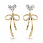 SVORA gold-tone stainless steel dangle earrings with cubic zirconia heart tops and bow drops.