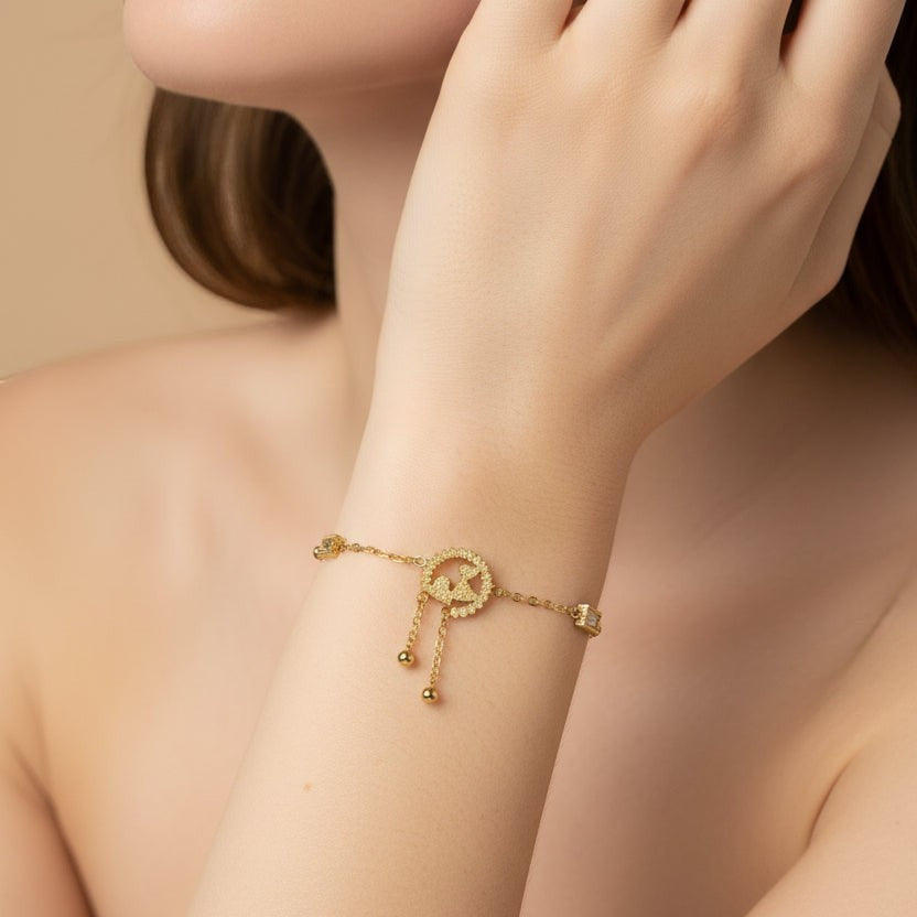 SVORA gold plated stainless steel bracelet with three heart charms and baguette CZ accents. Adjustable.