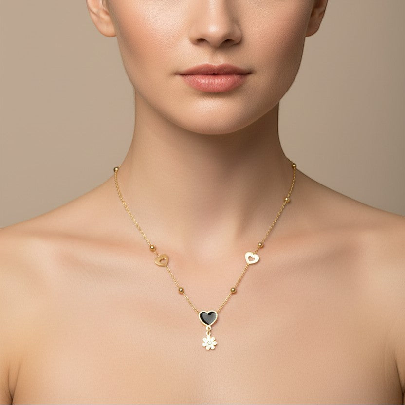 SVORA gold-tone stainless steel necklace with black enamel heart and daisy charms, featuring hollow heart cutouts.