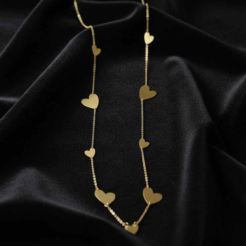 SVORA gold-tone stainless steel drape necklace with multiple polished heart charms on a delicate chain.