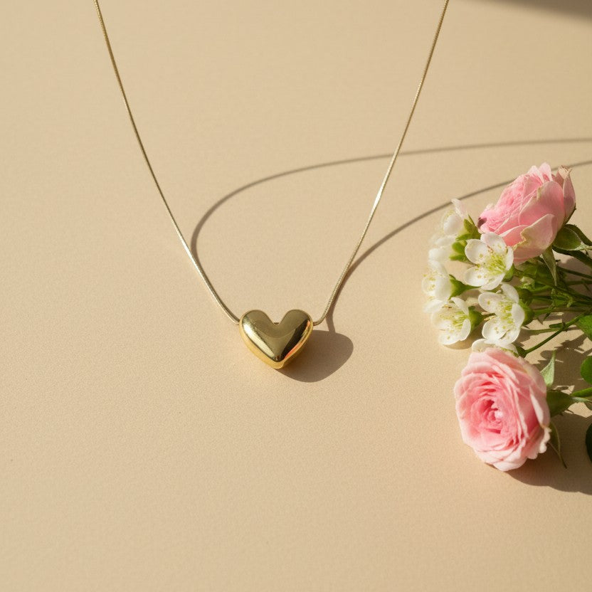 SVORA gold-plated stainless steel dew drop heart necklace on a delicate chain, styled with pink roses.