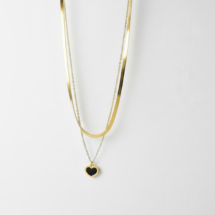 SVORA gold layered necklace with a black enamel heart pendant and snake chain. Stainless steel with 18k gold plating.