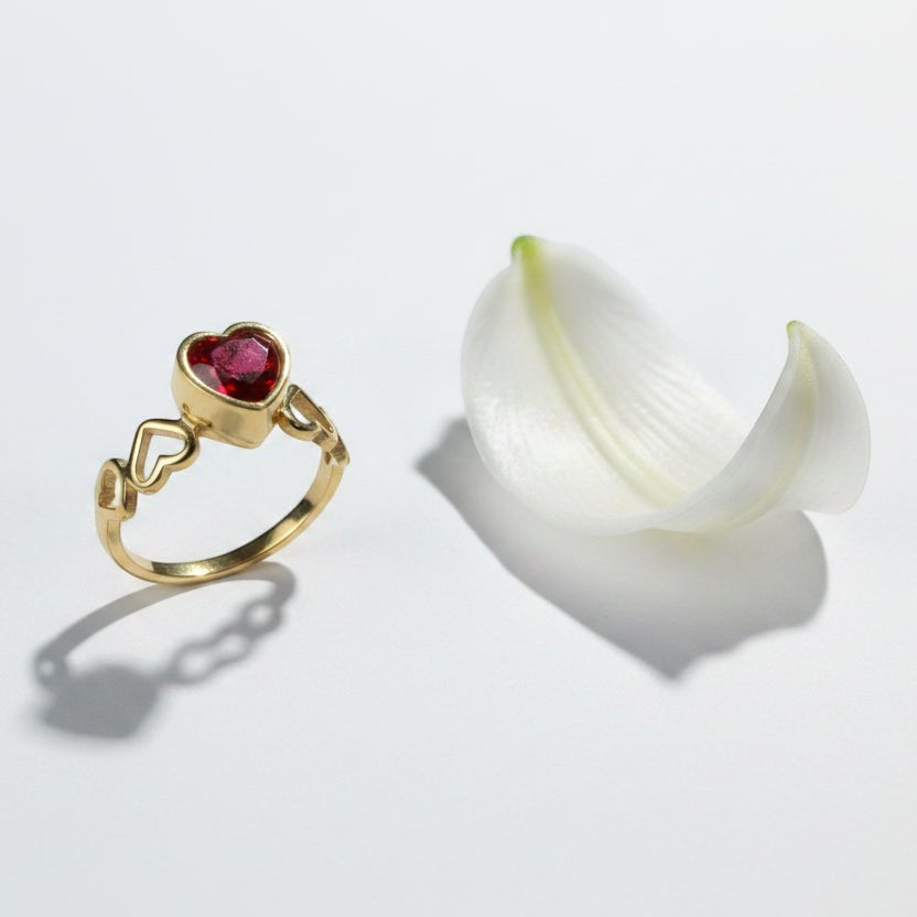 SVORA gold-plated stainless steel ring with a ruby red heart-shaped cubic zirconia and heart cutouts on the band.