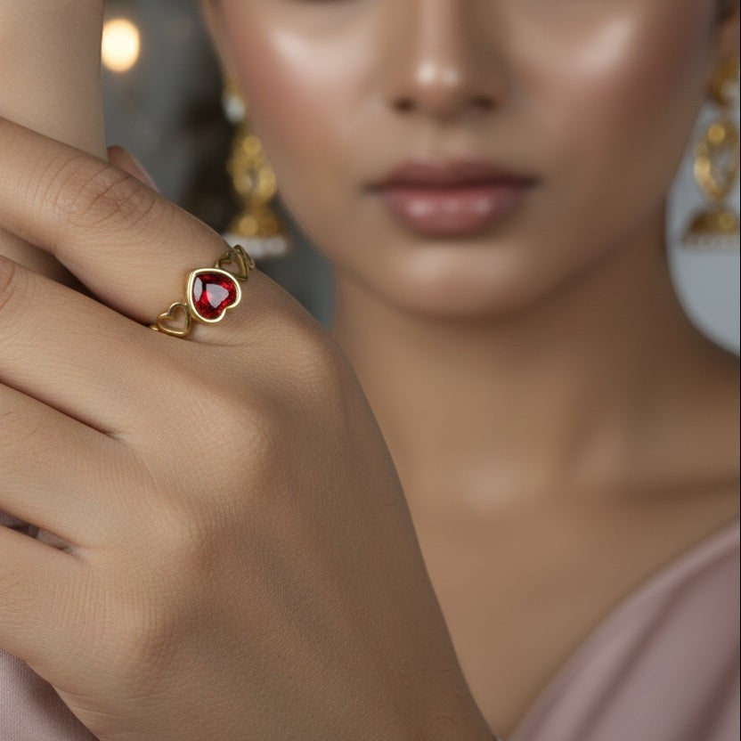 SVORA gold-plated stainless steel ring with a ruby red heart-shaped cubic zirconia and small heart details.