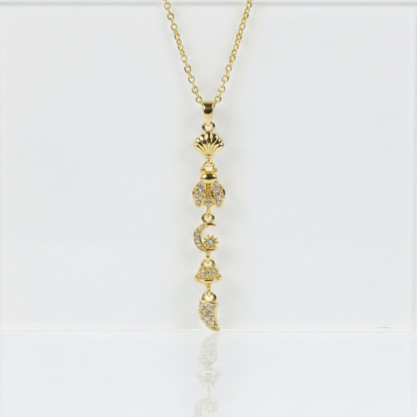 SVORA gold lariat necklace with shell, bee, moon, bell, and horn charms. 18K gold plated stainless steel.