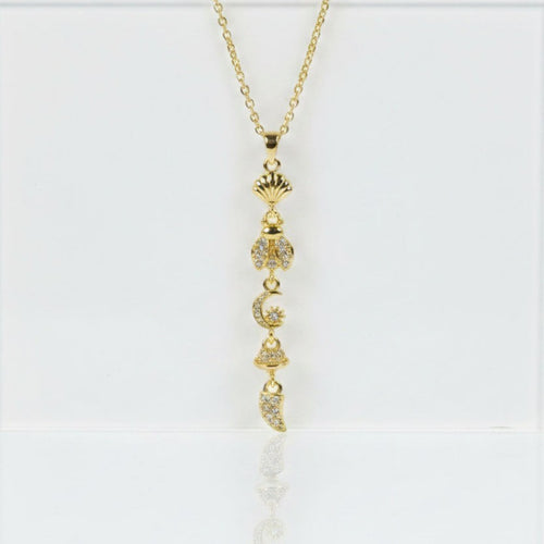 SVORA gold lariat necklace with shell, bee, moon, bell, and horn charms. 18K gold plated stainless steel.