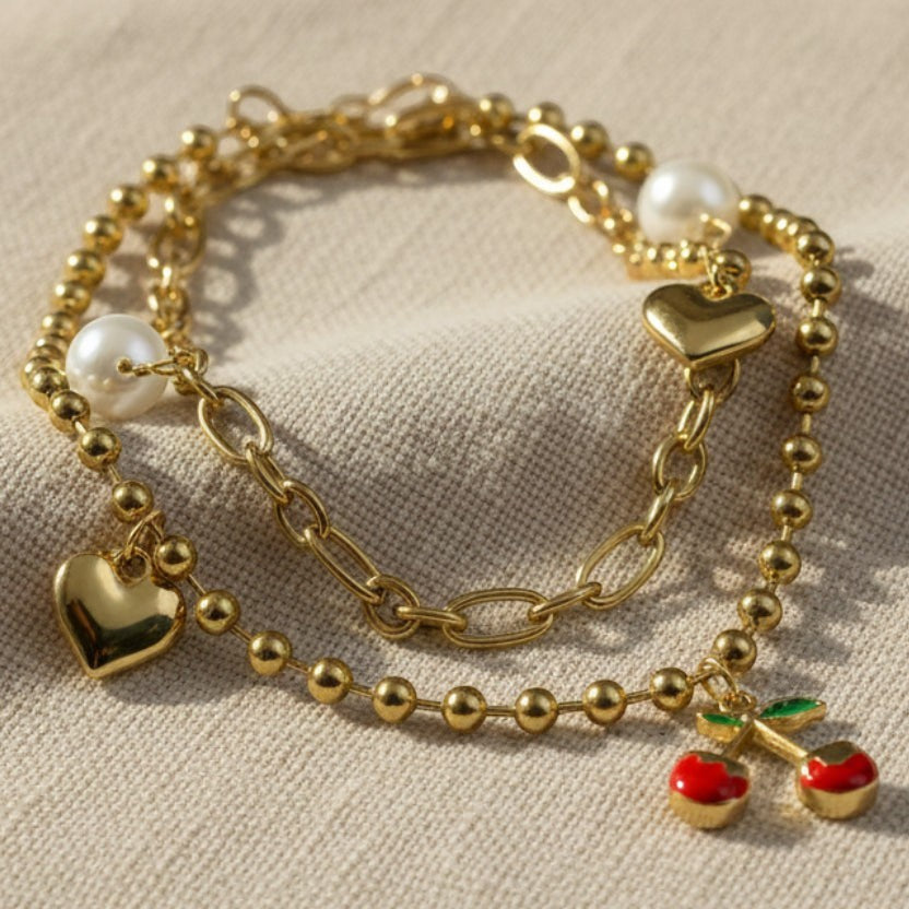 SVORA gold layered necklace with paperclip and ball-bead chains, featuring pearl, heart, and cherry charms.