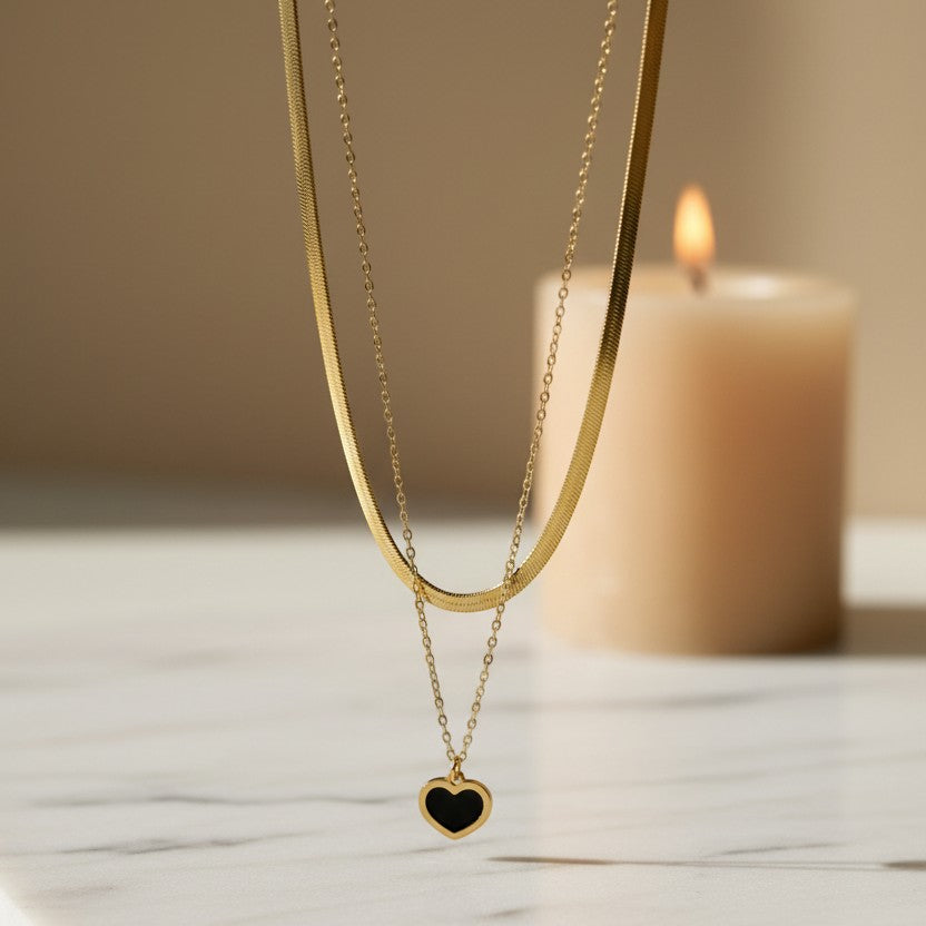 SVORA gold layered necklace with a snake chain and a black enamel heart pendant. Stainless steel with 18k gold plating.