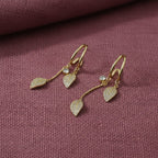 SVORA gold-plated stainless steel dangle earrings with leaf-shaped charms and clear crystals.