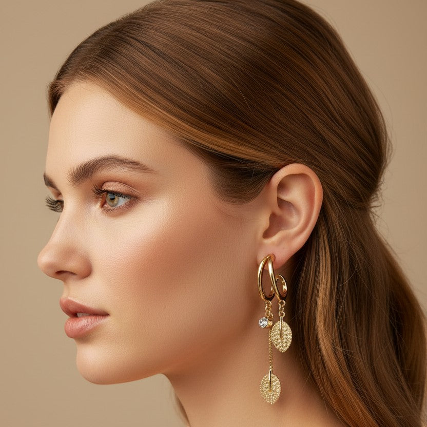 SVORA gold-plated stainless steel dangle earrings with leaf motifs and crystal accents.
