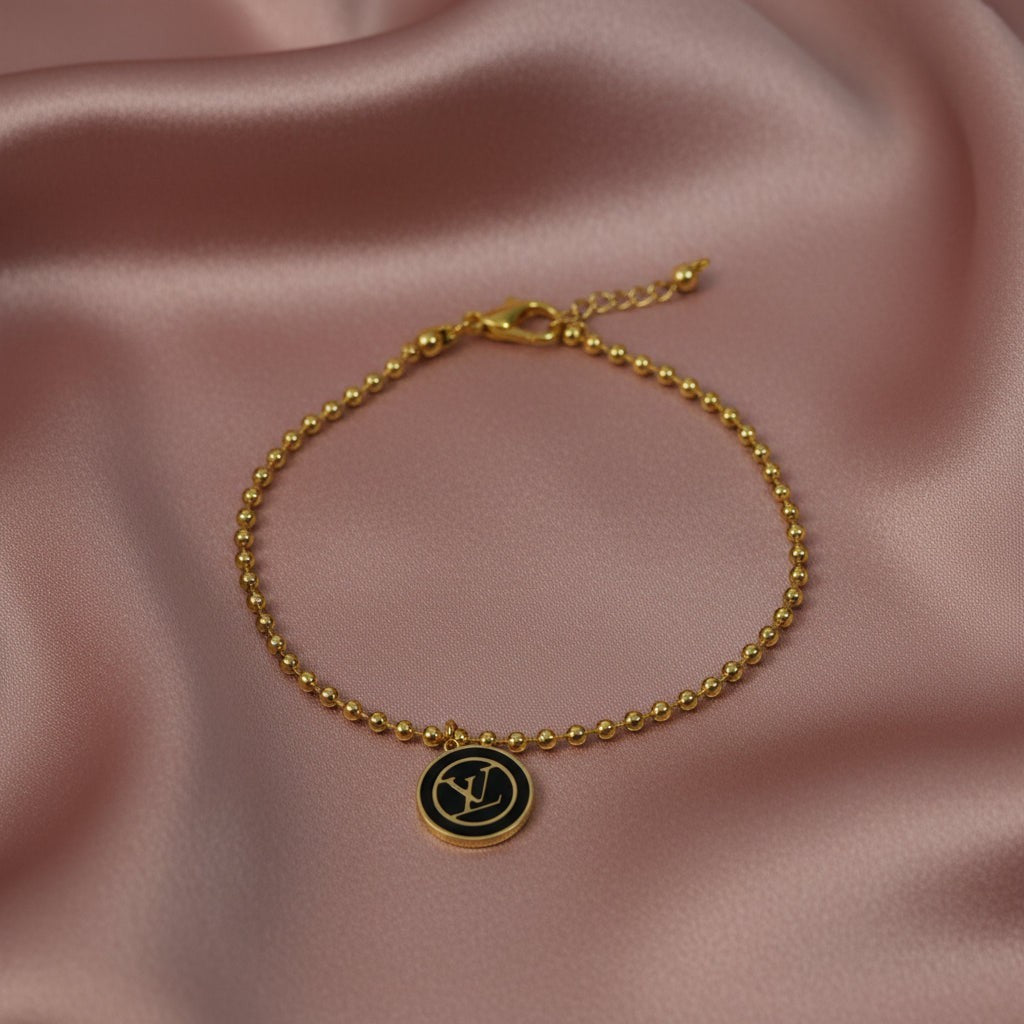SVORA gold ball bead chain bracelet with black monogram disc charm. 18K gold plated, stainless steel.