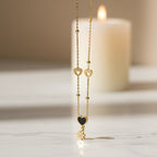 SVORA gold necklace with black enamel heart, daisy charm, and hollow heart details. Stainless steel, 18k gold plated.