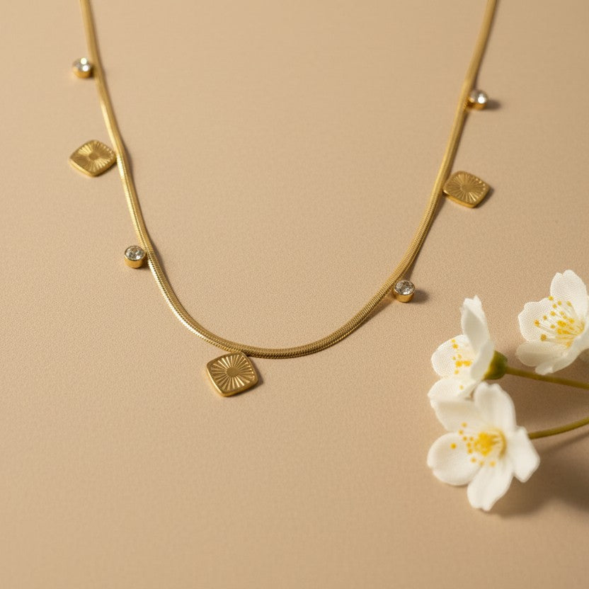 SVORA gold snake chain necklace with square charms and clear stone accents. 18k gold plated stainless steel.