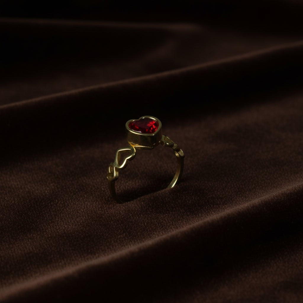 SVORA gold-plated stainless steel ring with a red heart-shaped cubic zirconia and heart details on the band.