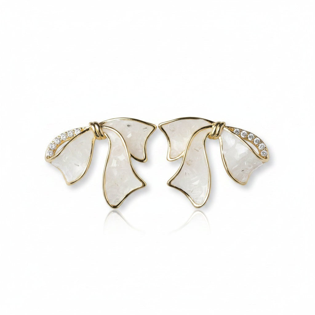 SVORA sculptural gold ribbon earrings with white stone inlay and pavé cubic zirconia accents.