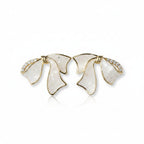SVORA sculptural gold ribbon earrings with white stone inlay and pavé cubic zirconia accents.