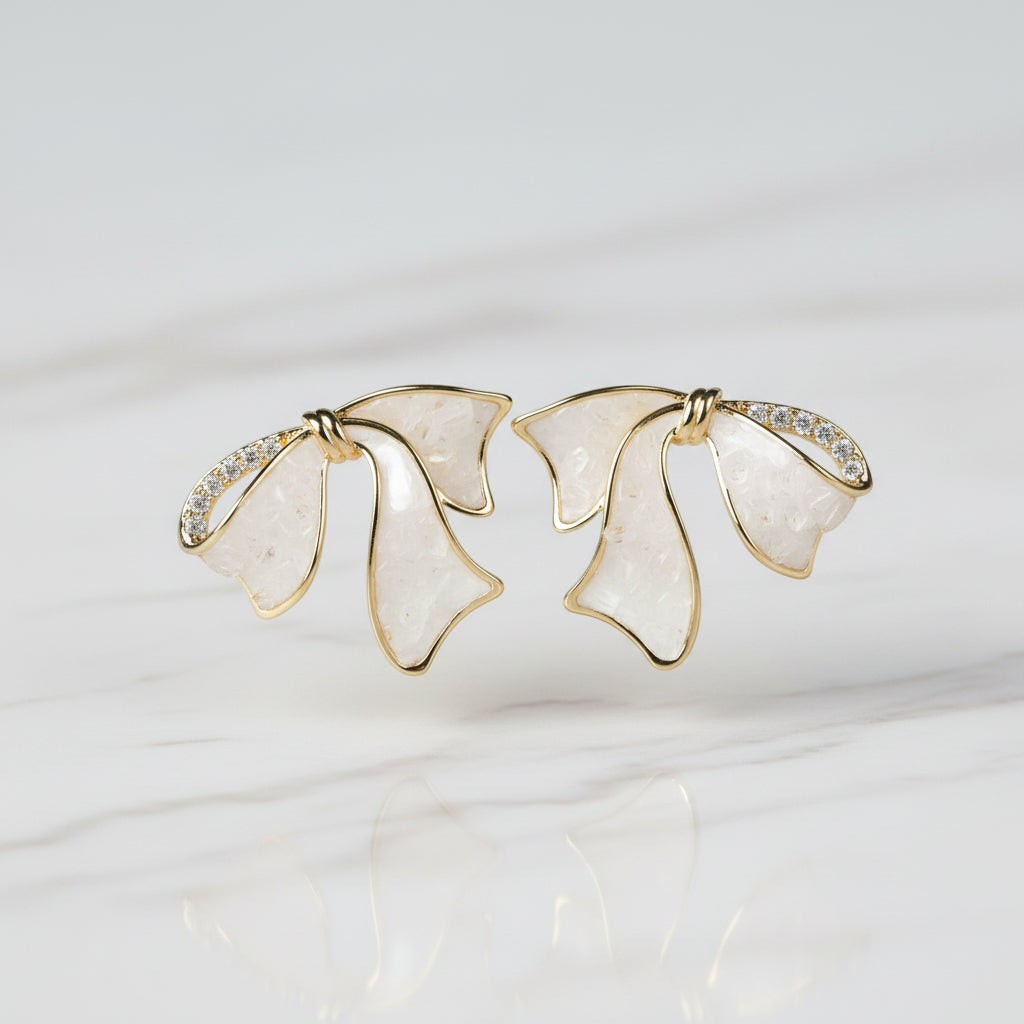 SVORA sculptural gold ribbon stud earrings with white stone and pavé cubic zirconia accents.