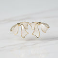 SVORA sculptural gold ribbon stud earrings with white stone and pavé cubic zirconia accents.