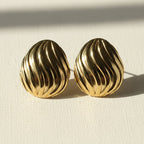SVORA sculpted shell-dome gold stud earrings with ribbed surface detail and high polish finish.