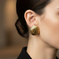SVORA sculpted gold-tone shell dome stud earrings with ribbed surface detail and high polish finish.