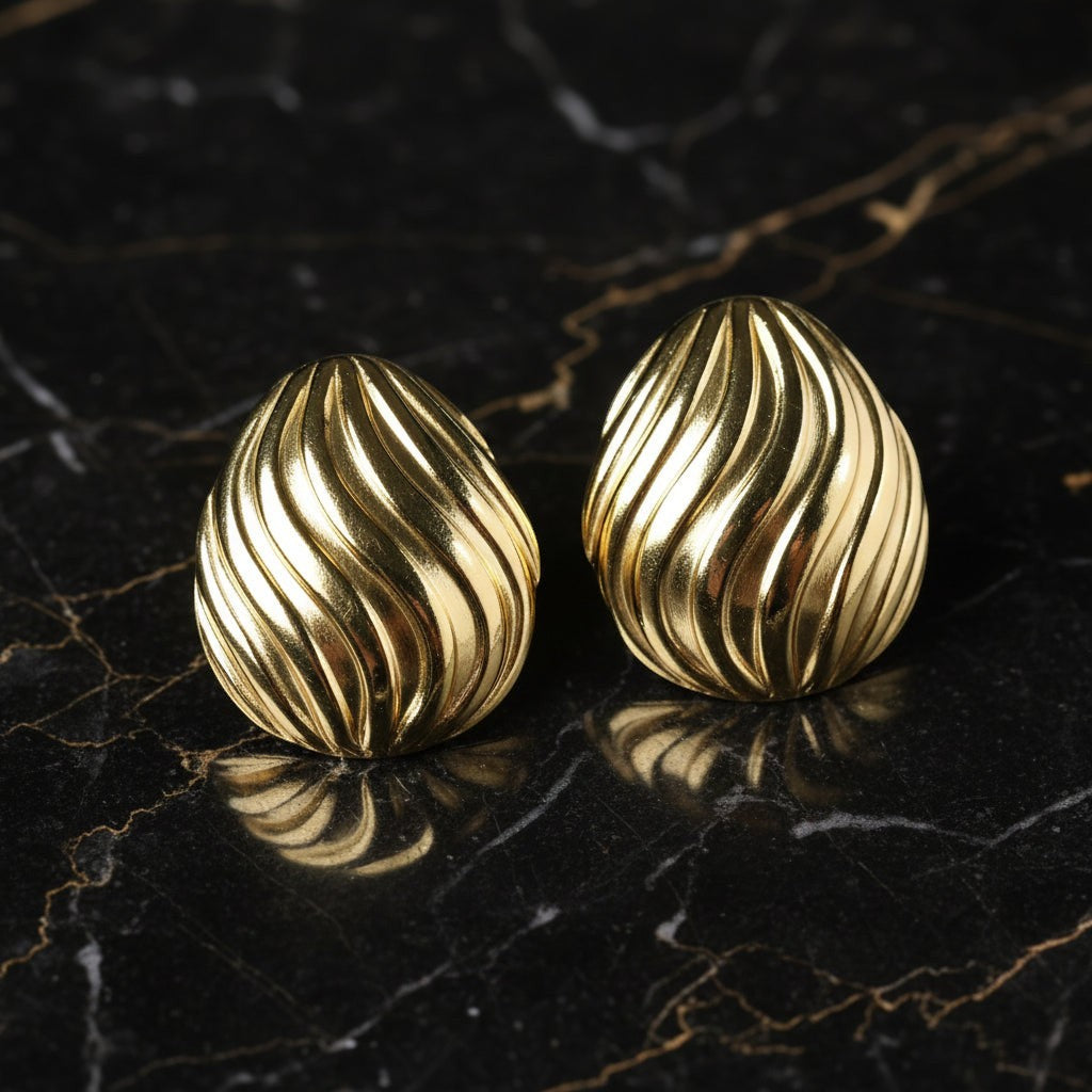 SVORA sculpted shell-dome gold stud earrings with ribbed surface detail. Polished gold-tone stainless steel.