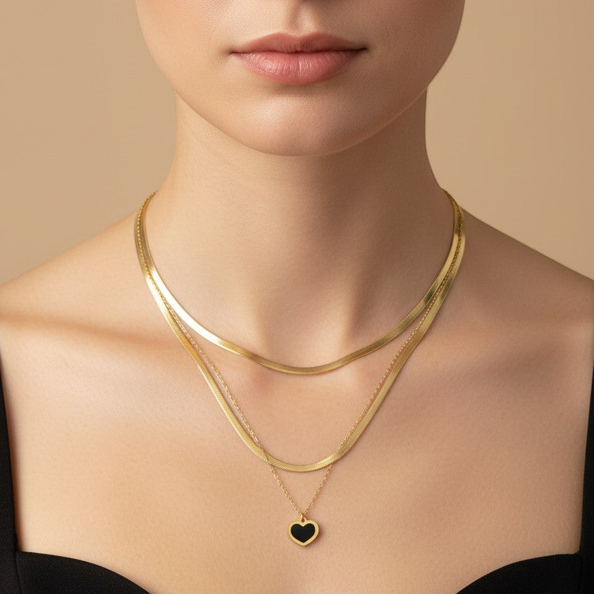 SVORA layered gold snake chain necklace with black enamel heart pendant. Stainless steel with 18k gold plating.