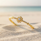 SVORA gold-plated stainless steel bracelet with a central solitaire CZ stone and floral design, set on a sandy beach.