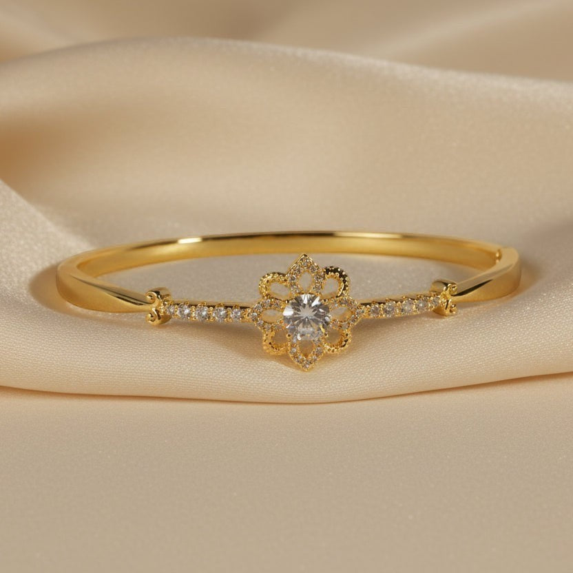 SVORA gold-plated stainless steel hinged bracelet with a central flower design featuring a clear cubic zirconia and smaller CZ accents.