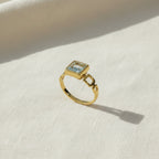 SVORA gold ring with a square-cut blue stone and open square link band. 18K gold plated stainless steel.