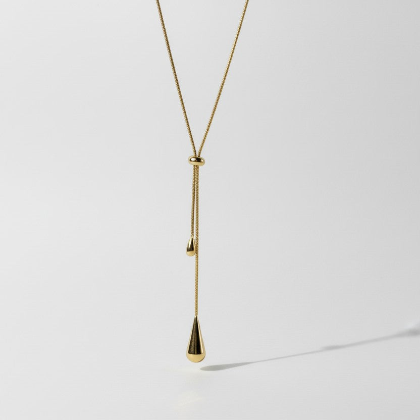 SVORA gold teardrop lariat necklace with adjustable snake chain and polished charms.