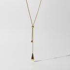 SVORA gold teardrop lariat necklace with adjustable snake chain and polished charms.