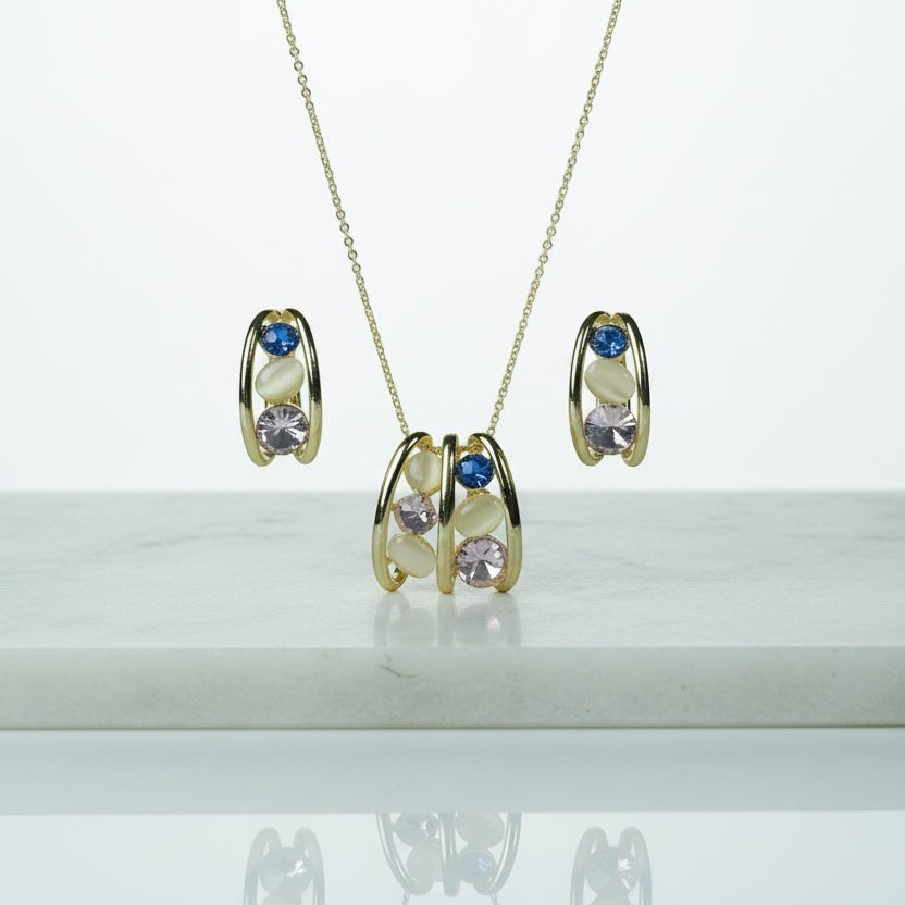 SVORA gold tone necklace and earrings set with pink, blue, and cream cabochon stones in a caged design.