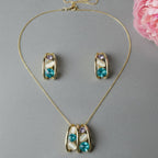 SVORA gold-tone necklace and earrings set with teal blue, lavender, and cream cabochon stones in a caged design.