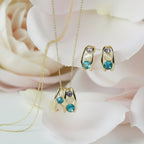 SVORA gold-tone necklace and earrings set with blue, lavender, and cream cabochon stones in a caged design.