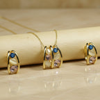 SVORA gold tone necklace and earrings set with pink, blue, and cream stones. Stainless steel, 18K gold plating.