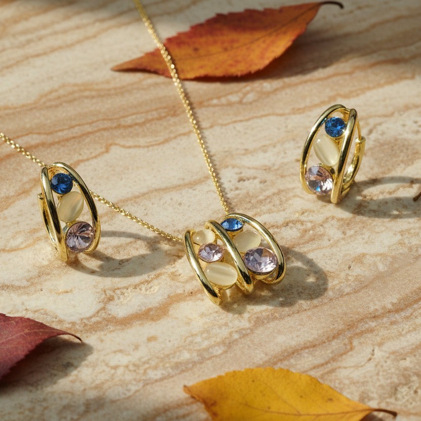 SVORA gold tone necklace and earrings set with pink, blue, and cream stones. Stainless steel with 18K gold plating.