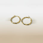 SVORA gold twisted hoop earrings with a polished finish and rounded silhouette. Textured detail adds contemporary style.