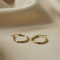 SVORA gold twisted hoop earrings with a polished finish and rounded silhouette. Stainless steel with 18K gold tone plating.
