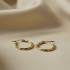 SVORA gold twisted hoop earrings with a polished finish and rounded silhouette. Stainless steel with 18K gold tone plating.