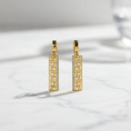 SVORA gold-tone stainless steel huggie hoop earrings with Greek key cut-out drop and pavé cubic zirconia.
