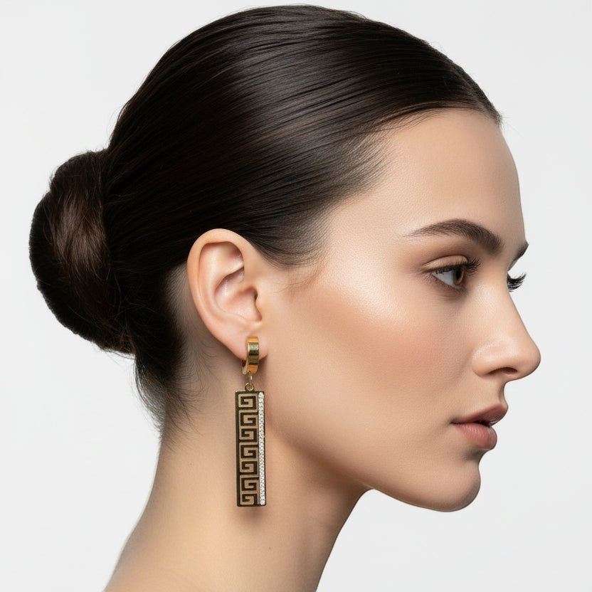 SVORA gold tone stainless steel huggie hoop earrings with Greek key cut-out drop and cubic zirconia.
